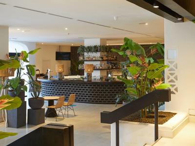 Moderner Hotel-Lobbybereich mit Sitzgelegenheiten und Pflanzen neben der Rezeption.