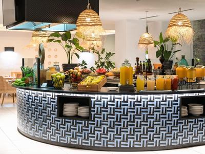 Bar moderno con frutas, bebidas e iluminación decorativa en una habitación luminosa.