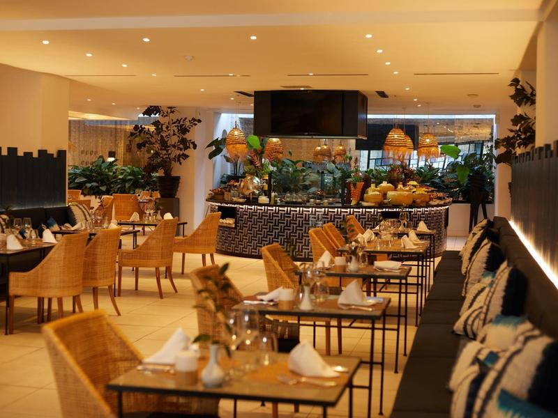 Área de restaurante de hotel decorada modernamente con mesas, sillas e iluminación elegante.