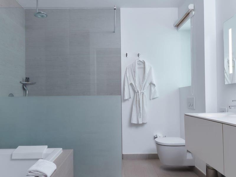 Salle de bain moderne avec paroi de douche en verre dépoli et serviettes blanches.