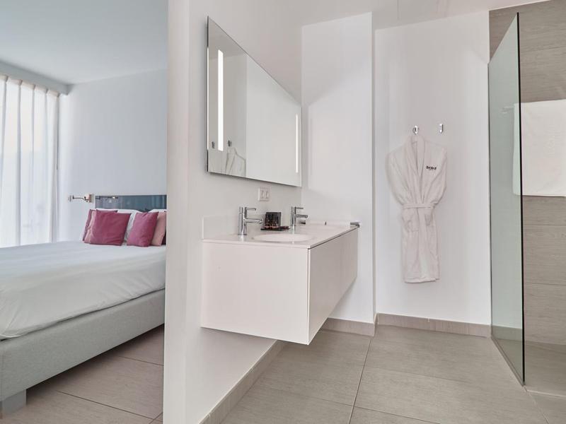 Salle de bain moderne avec lavabo, miroir et douche à l'italienne dans une chambre d'hôtel.