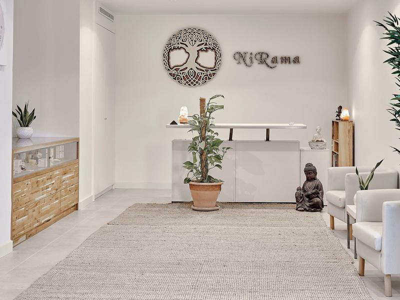 Hall d'hôtel lumineux avec plantes, fauteuils blancs et décorations murales.