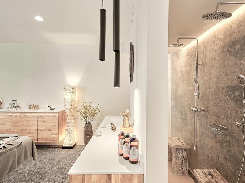 Chambre d'hôtel moderne avec commode en bois et douche élégante avec paroi en verre.