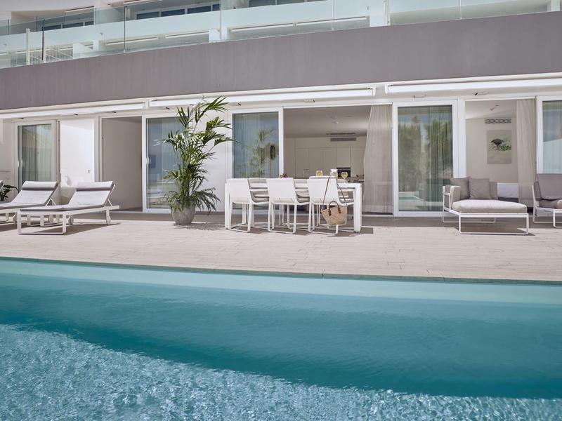 Piscine d'hôtel moderne avec transats et espace de restauration devant de grandes baies vitrées.