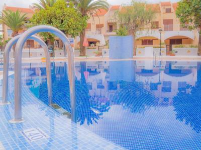 Rundes Schwimmbecken mit blauem Wasser und Metallleiter, umgeben von Bäumen und Gebäuden.