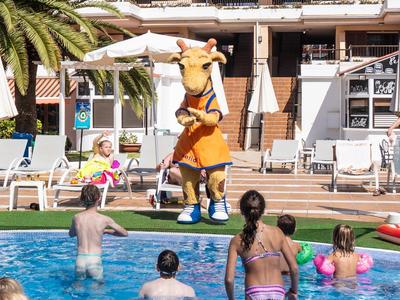 Menschen planschen im Pool, eine Person in Löwenkostüm macht einen Handstand auf der Poolterrasse.
