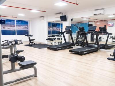 Nowoczesna siłownia z bieżniami i sprzętem do ćwiczeń w jasnej, otwartej przestrzeni.