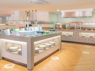 Modernes Buffet mit verschiedenen Speisen, helles Holzparkett und gedeckte Raumfarben.