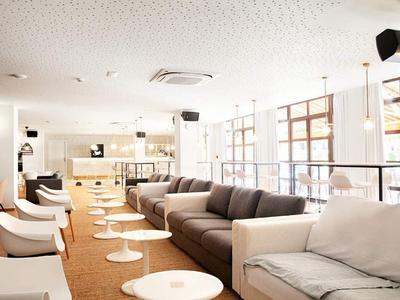 Helles, modernes Wohnzimmer mit grauen Sofas, weißen Sesseln und runden Tischen auf braunem Teppich.