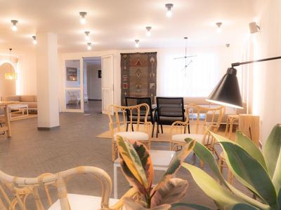 Heller, offener Raum mit Holzstühlen, Pflanzen, Lampen und einer gemütlichen Sitzecke.