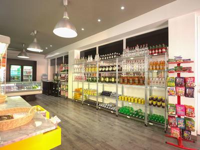 Heller Laden mit Regalen voller Getränke und Snacks, moderner Boden und Deckenlampen.