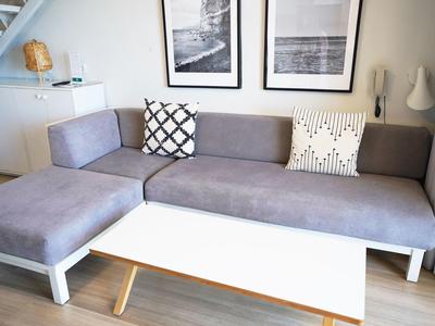 Modernes Wohnzimmer mit grauem Ecksofa, weißem Couchtisch und zwei schwarz-weißen Kissen.