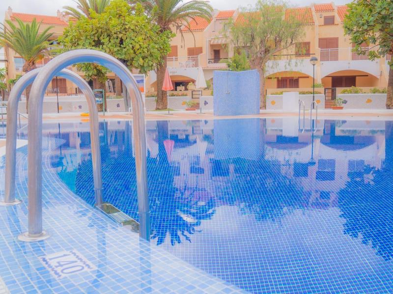 Rundes Schwimmbecken mit blauem Wasser und Metallleiter, umgeben von Bäumen und Gebäuden.