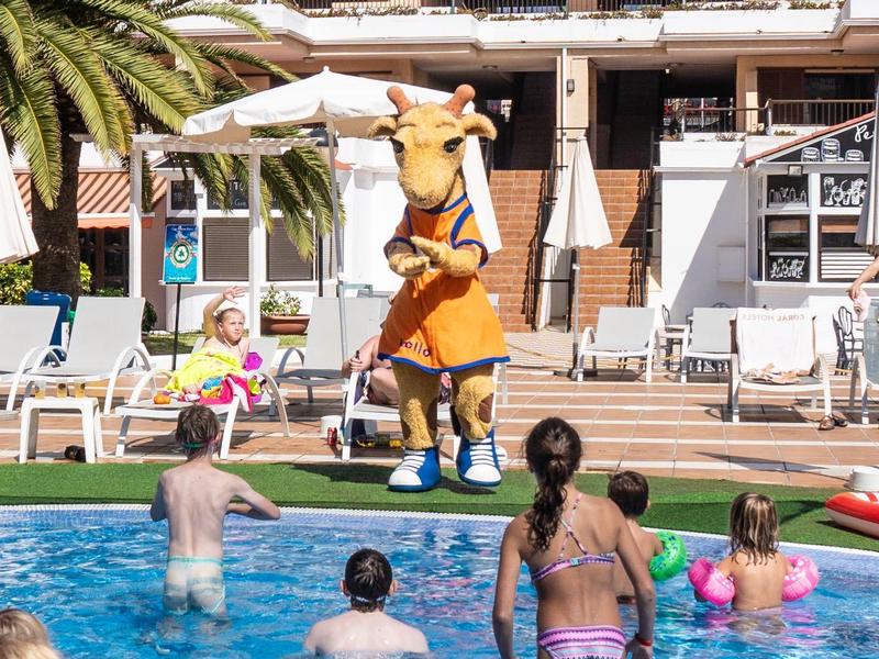 Menschen planschen im Pool, eine Person in Löwenkostüm macht einen Handstand auf der Poolterrasse.