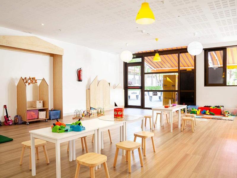 Heller, freundlicher Gruppenraum mit Stühlen, Tischen, Spielsachen und großen Fenstern.