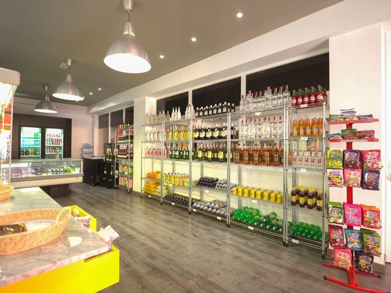 Heller Laden mit Regalen voller Getränke und Snacks, moderner Boden und Deckenlampen.