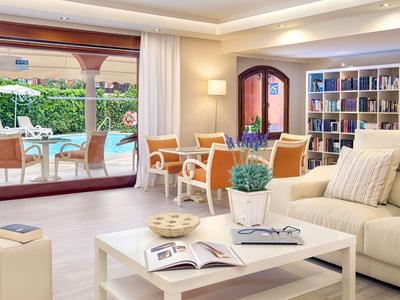 Salon lumineux avec canapé, table basse, fauteuils et vue sur la terrasse et le jardin.