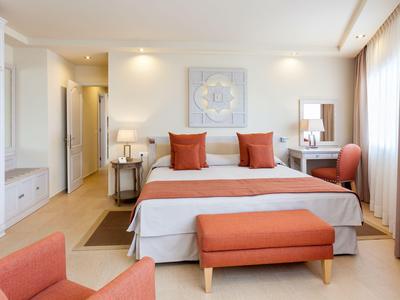 Chambre d'hôtel lumineuse avec lit double, accents orange et grande fenêtre avec rideaux.