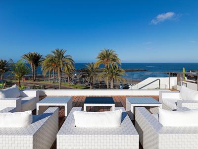 Luksusowe białe meble na tarasie z widokiem na morze i palmy pod niebieskim niebem