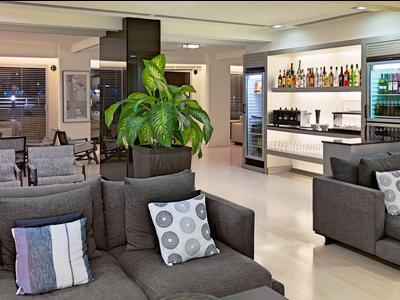 Lobby d'hotel moderna con divani grigi, cuscini decorativi e area bar sullo sfondo