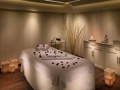 Una stanza spa tranquilla con un lettino da massaggio decorato con petali di rosa e luce soffusa.