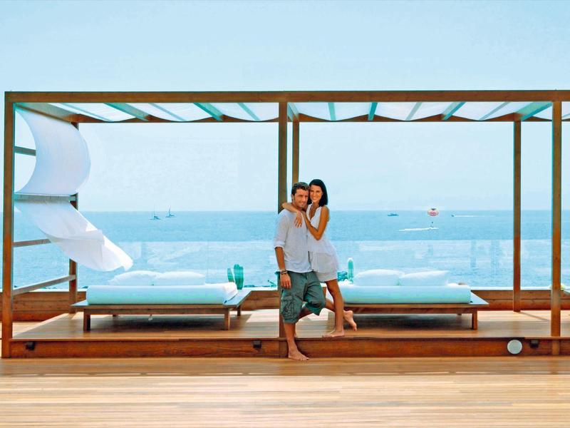 Para siedzi na drewnianym tarasie z widokiem na morze w nadmorskim kurorcie.