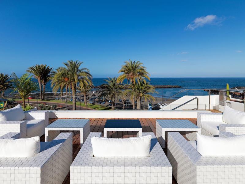 Luksusowe białe meble na tarasie z widokiem na morze i palmy pod niebieskim niebem