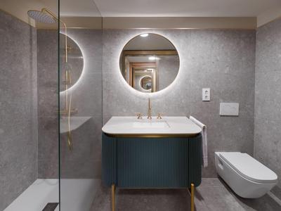 Nowoczesna łazienka z okrągłym podświetlanym lustrem i stylową umywalką w hotelu.