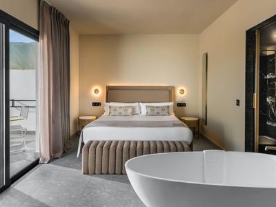 Nowoczesny pokój hotelowy z podwójnym łóżkiem, wanną i balkonem z widokiem na góry.