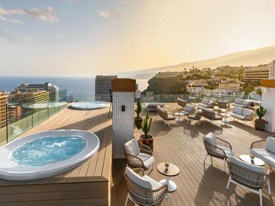 Dachterrasse mit Whirlpool, Sitzgelegenheiten und Meerblick bei Sonnenuntergang.