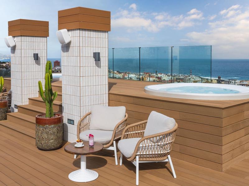 Moderne Terrasse mit Holzdeck, Whirlpool, gemütlichem Sitzbereich und Blick aufs Meer.
