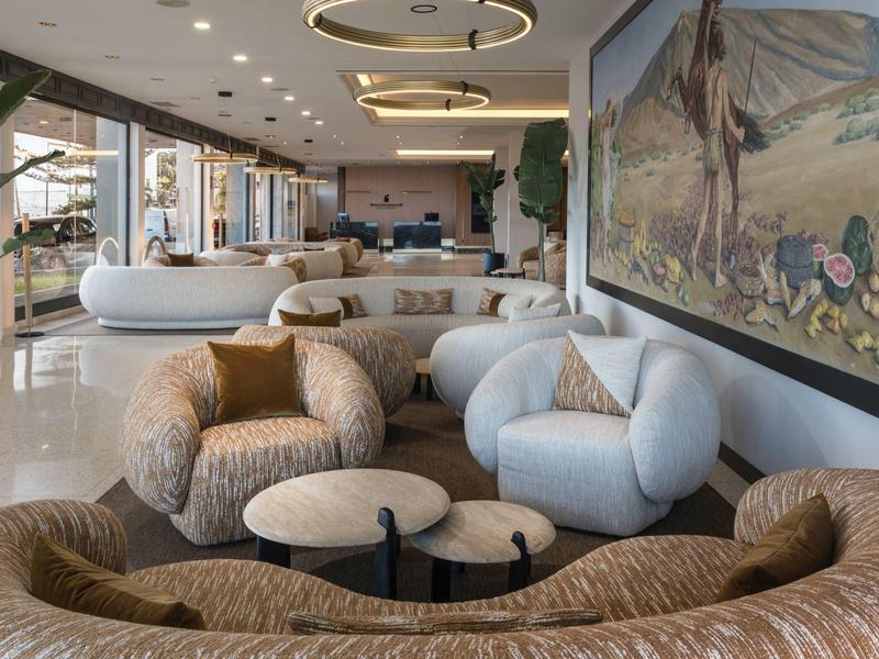 Moderne Lobby mit geschwungenen Sofas in Beige und Hellblau, runden Tischen und großem Wandbild.