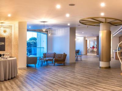 Moderner Raum mit hellen Holzböden, runden Tischen, Stühlen und Deckenlampen in warmem Licht.