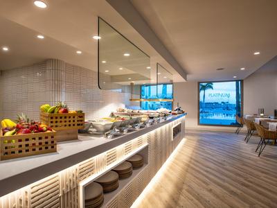 Moderne Cafeteria mit Buffet, hellem Holzfußboden und großem Fenster mit Blick ins Freie.