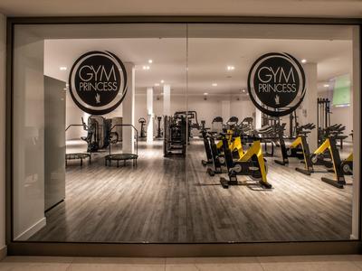 Widok na nowoczesną siłownię z rowerami stacjonarnymi i lustrzaną ścianą.