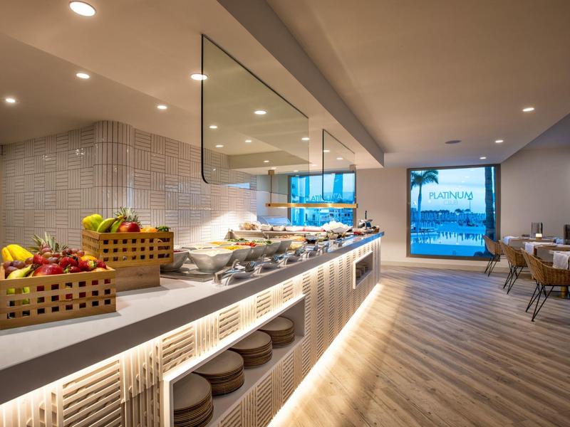Moderne Cafeteria mit Buffet, hellem Holzfußboden und großem Fenster mit Blick ins Freie.