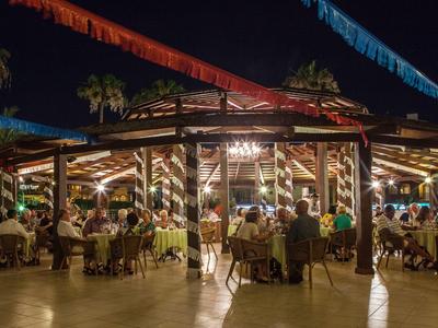 Lit outdoor restaurant with colorful streamers and guests at night.