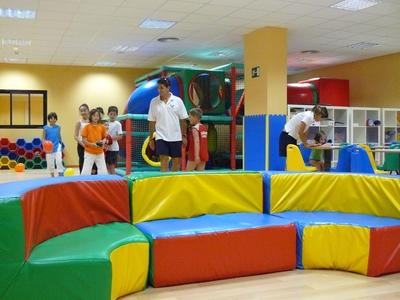 Area giochi colorata in un hotel con posti a sedere e bambini che giocano.