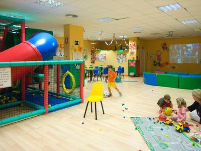Area giochi per bambini con struttura da arrampicata e assistente che gioca con i bambini