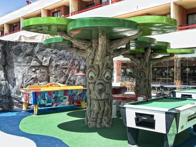Outdoor area with foosball and game table under large tree-shaped umbrellas