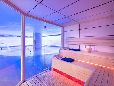 Area benessere moderna con sauna e vista su una piscina attraverso grandi finestre.