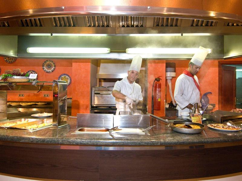 Due chef che preparano cibo in una cucina d'hotel ben attrezzata.