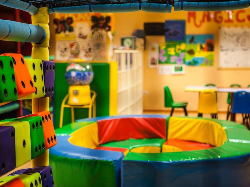 Area giochi colorata per bambini con sedute morbide e sedie in una sala giochi dell'hotel.