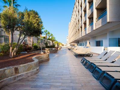 Nowoczesny balkon hotelowy z leżakami i roślinami pod czystym niebem.