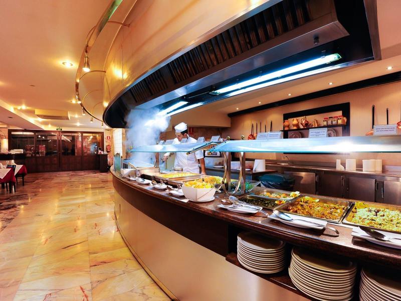 Buffetlinie in einem gut beleuchteten Restaurant mit warmen Farben und gedeckten Tischen.