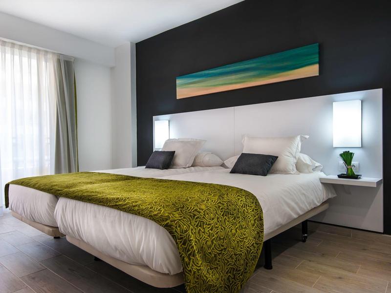 Modernes Doppelbett mit weißer Bettwäsche, grüner Decke und schwarzer Akzentwand im Schlafzimmer.