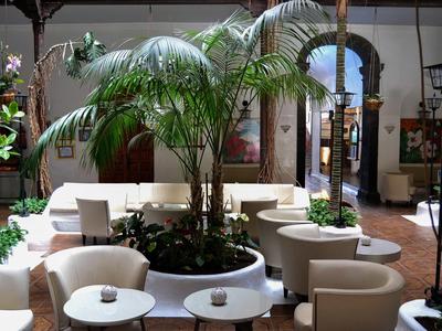 Un patio luminoso con plantas y asientos blancos en un ambiente relajado.