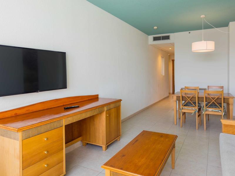 Nowoczesny salon z drewnianymi meblami, telewizorem i jadalnią w jasnym pomieszczeniu.