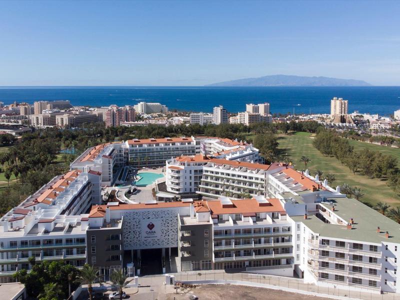 Widok z lotu ptaka na duży hotel nad morzem z otaczającym miastem i terenami zielonymi.