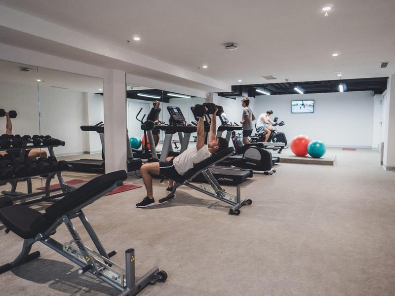 Nowoczesna siłownia z wyposażeniem i osobą podnoszącą ciężary.